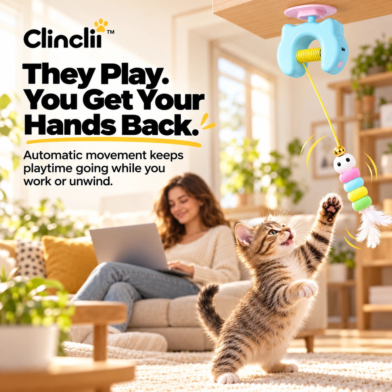 Cat chasing a Clinclii toy while a cat owner works nearby on a laptop